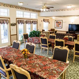 A community dining room with floral tablecloths and arranged seating.
