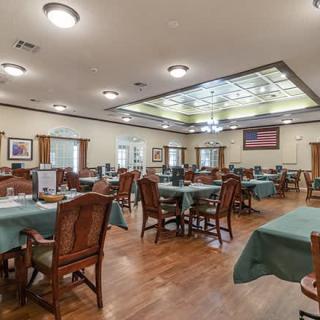 A spacious dining area with neatly arranged tables and chairs, featuring wooden floors and ambient lighting.
