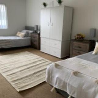 A neat and tidy bedroom with two single beds, a wardrobe, and a rug on the floor.
