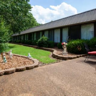 A well-maintained building with a landscaped garden, featuring a pathway surrounded by greenery and cloudy skies.