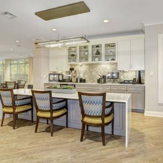 A modern kitchen with an island and bar stools, featuring stylish cabinetry and a contemporary lighting fixture.