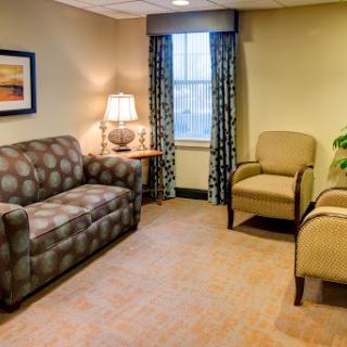 A cozy waiting room featuring a patterned sofa, comfortable chairs, and a warm atmosphere.