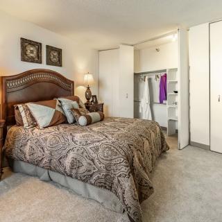 A cozy bedroom interior with a large bed and an open closet.