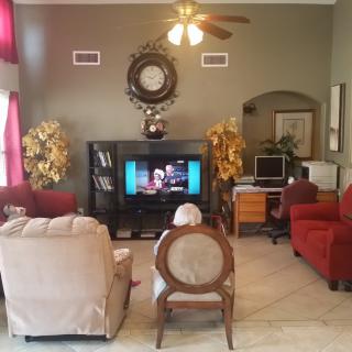 A cozy living room with people watching television, featuring comfortable seating and decorative elements.
