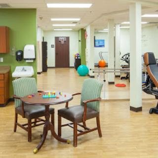 A spacious therapy room equipped with various rehabilitation tools and comfortable seating.