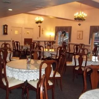An empty dining room with elegant chandeliers and neatly arranged tables and chairs.