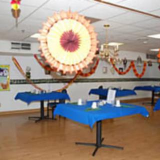 A festively decorated room with tables covered in blue cloth, ready for an event.
