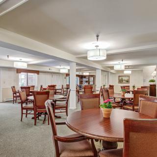 A spacious dining area with wooden tables and chairs, well-lit and elegantly furnished.