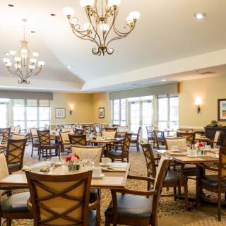 A spacious dining room with neatly arranged tables and elegant chandeliers.