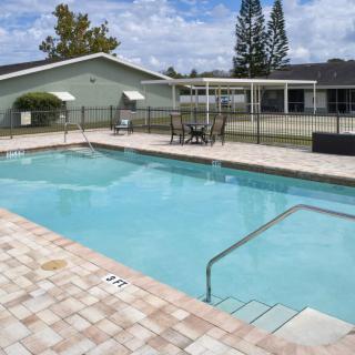 A serene outdoor swimming pool area with surrounding patio furniture and greenery.