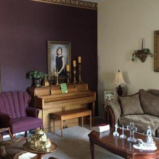 A cozy living room featuring a piano and portrait on the wall.