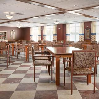 An inviting dining area with wooden tables and chairs, featuring a checkered floor and large windows.