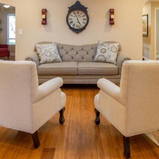 A cozy living room with a stylish sofa, two armchairs, and a decorative clock on the wall.