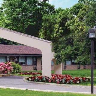 A landscaped entrance with flowers and trees in front of a building.