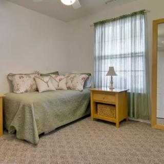 A cozy bedroom with a single bed, nightstand, lamp, and window with curtains.