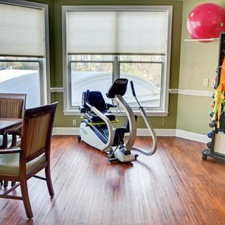 An indoor exercise space featuring an elliptical machine and therapy equipment.