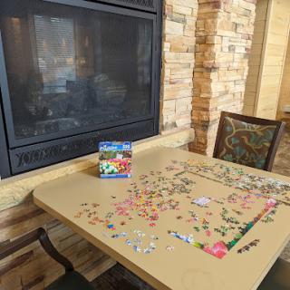A cozy indoor setting featuring a partially completed puzzle on a table next to a fireplace.