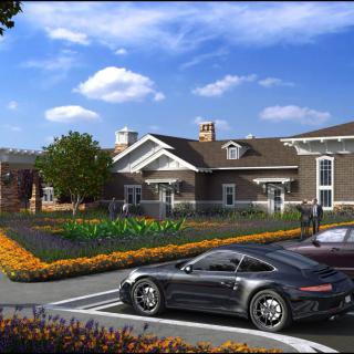 A modern house with a garden and parked cars under a clear blue sky.