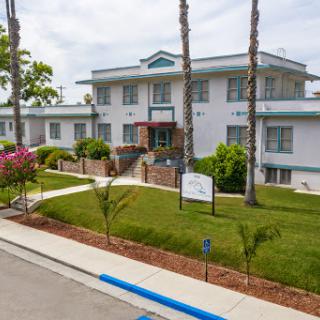 A well-maintained residential building surrounded by lush greenery and palm trees.