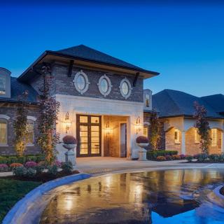 A stunning luxury mansion illuminated at dusk with elegant architectural details and beautiful landscaping.