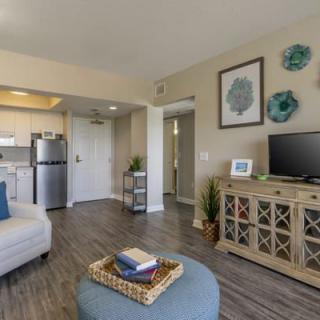 A cozy living area with an open kitchen, featuring modern decor and a television.