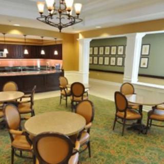 A cozy dining area with round tables and elegant chairs under a decorative chandelier.