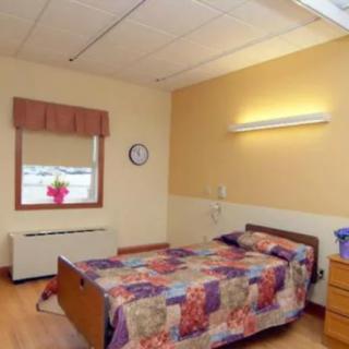A cozy hospital room with a single bed and a window providing natural light.