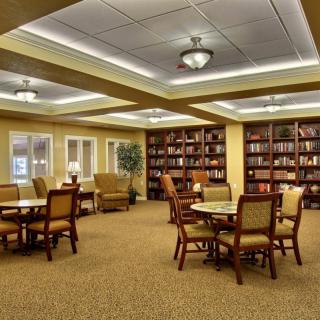 A cozy library interior with tables and chairs surrounded by shelves filled with books.