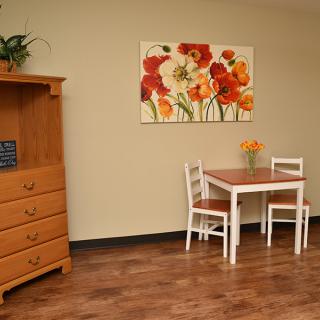 A cozy dining area featuring a small table with two chairs, complemented by vibrant floral artwork on the wall.