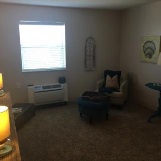 A cozy living room with an armchair, carpet, and decor.