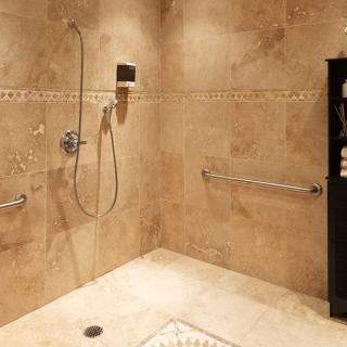 A modern walk-in shower with tiled walls and grab bars.