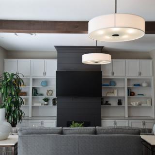 A modern living room with built-in shelving, a mounted television, and stylish lighting fixtures.