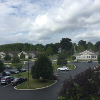 A view of a residential area featuring a parking lot, trees, and a cloudy sky.
