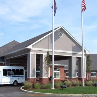 A building entrance with flags and a bus in front.