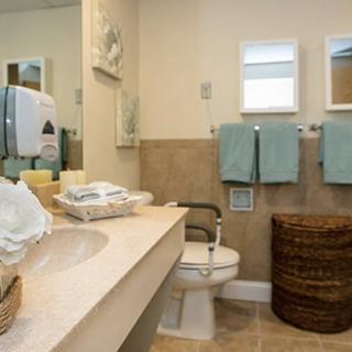 A clean and well-organized bathroom with a countertop, sink, mirror, and neatly arranged towels.