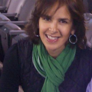 A woman with a green scarf smiling indoors.