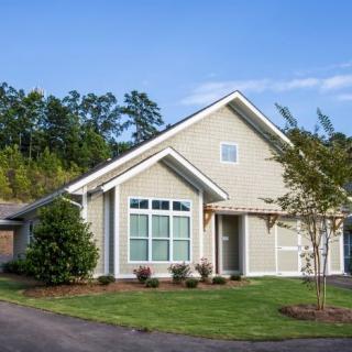 A suburban house with a neatly landscaped lawn and surrounding trees.