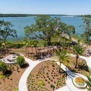 A scenic view of a landscaped garden by the waterfront with pathways and trees.