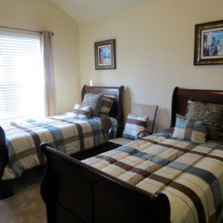 A cozy bedroom featuring two twin beds with plaid bedding and classic wooden frames.