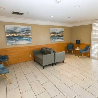 A modern lobby with tiled flooring, comfortable seating, and large artwork on the walls.