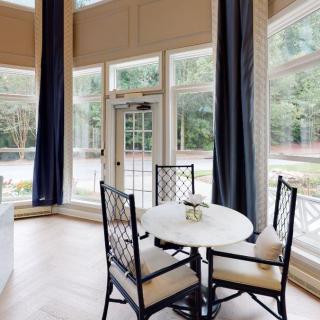 A bright and airy dining area with a round table, chairs, and large windows allowing natural light to fill the room.