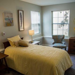 A cozy bedroom with a single bed, lamp, and window.