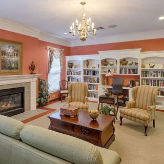 A cozy, traditional living room featuring a fireplace, bookshelves, and elegant seating.