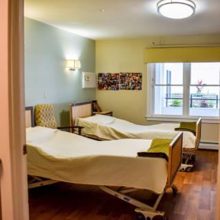 A hospital room with two patient beds and a window letting in natural light.