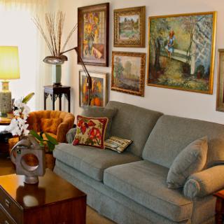 A cozy living room featuring a comfortable sofa, an array of art on the walls, and warm lighting.