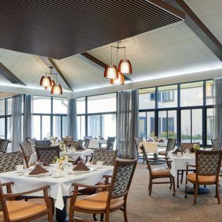 Elegant dining area with neatly arranged tables and chairs, featuring large windows and sophisticated lighting.