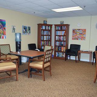A cozy office waiting room with chairs, a table, and bookshelves filled with books.