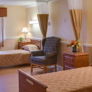 A cozy room with two single beds, a chair, and soft lighting.