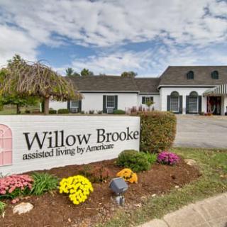 The exterior of Willow Brooke Assisted Living with a welcoming sign and landscaped entrance.