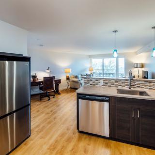 A modern open-layout kitchen with stainless steel appliances and a cozy living area.